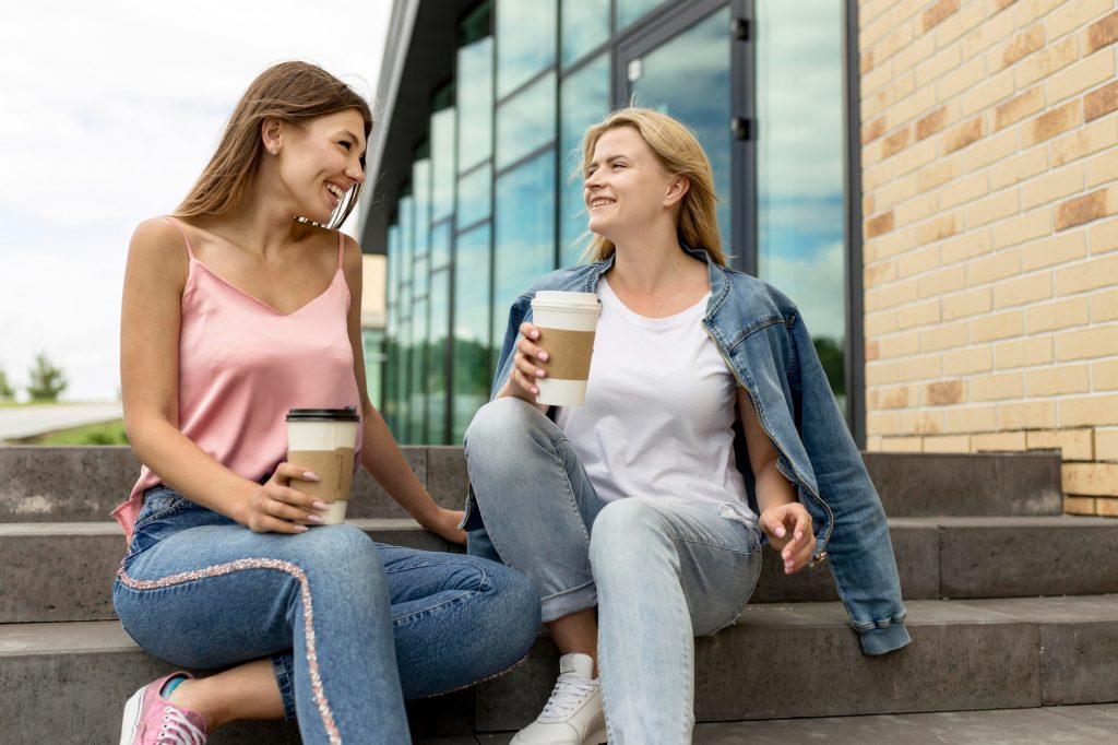 low angle girls chatting drinking their coffee